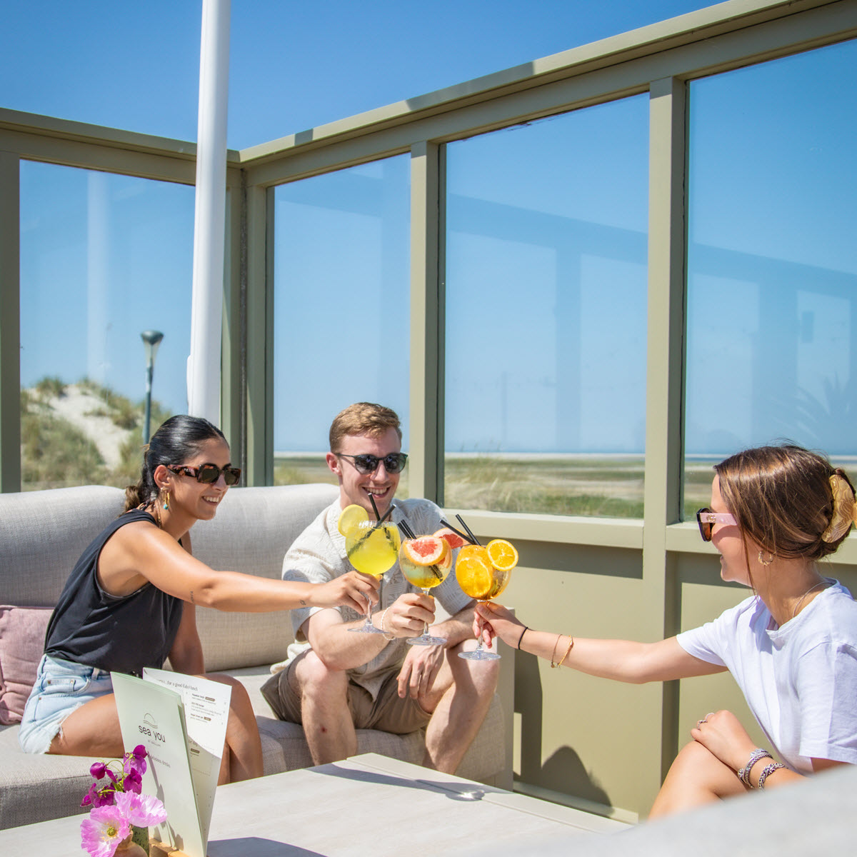 Serveerster van Sea You at Ballum brengt cocktails met uitzicht op de Amelander duinen